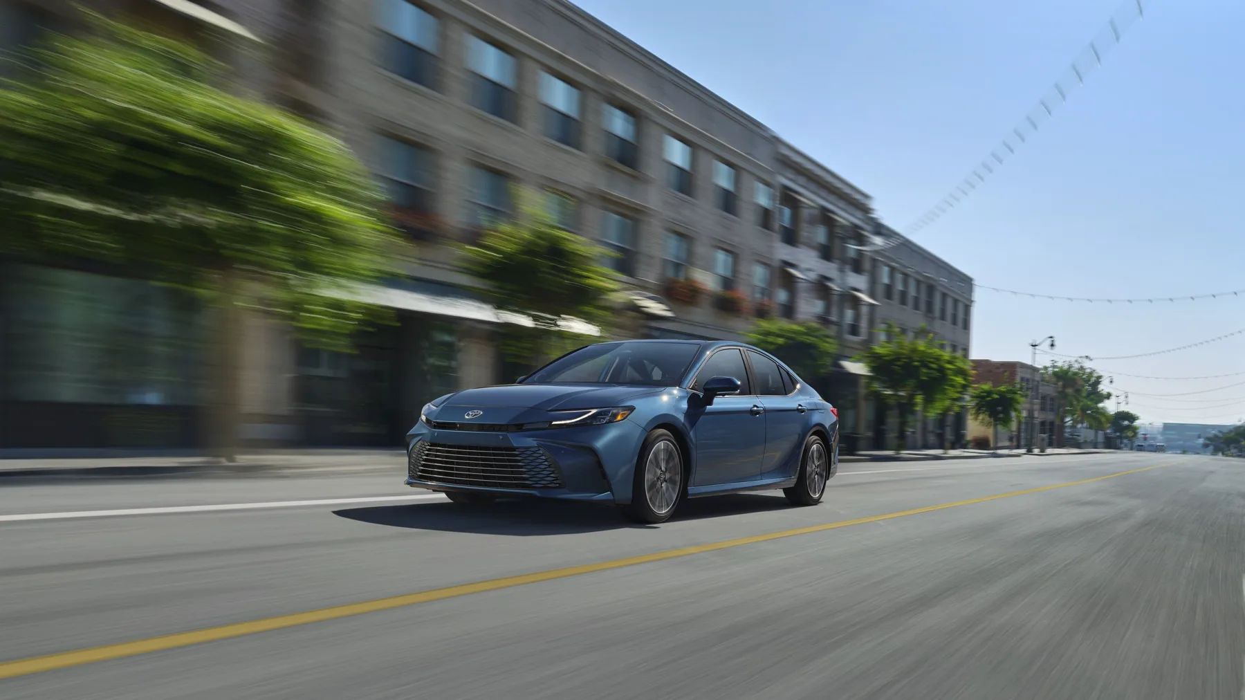 Blue 2025 Toyota Camry, front three-quarter view in motion