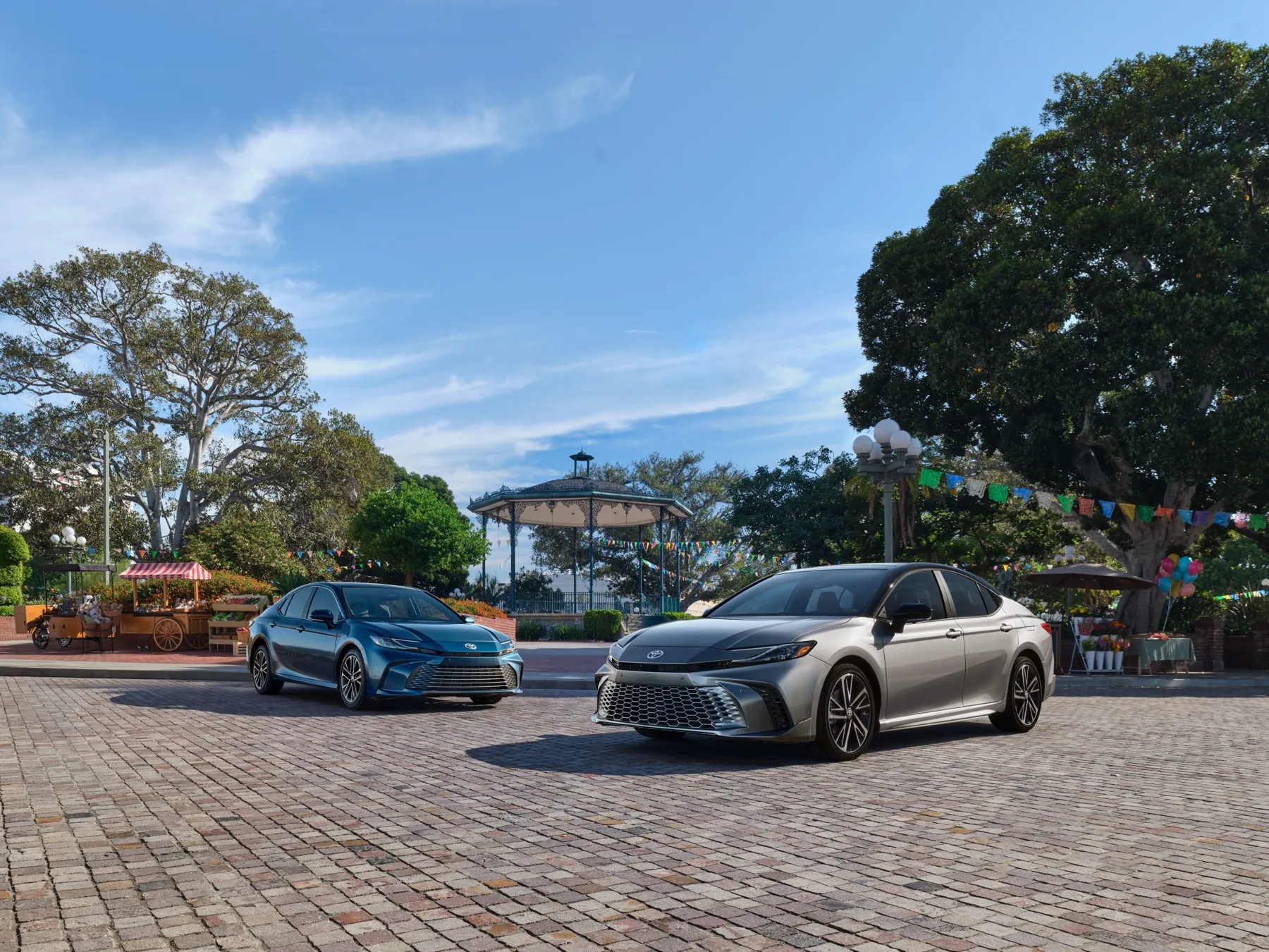 Silver and blue 2025 Toyota Camry hybrids parked in a plaza