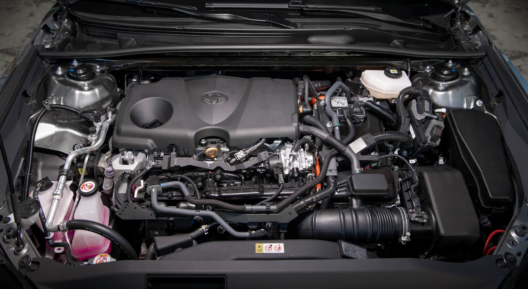 Engine bay of a 2025 Toyota Camry Hybrid with orange high-voltage cables