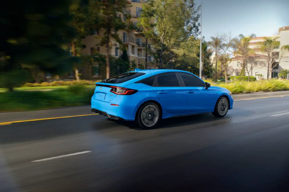 Blue 2025 Honda Civic Hatchback Sport Touring Hybrid in rear-quarter motion
