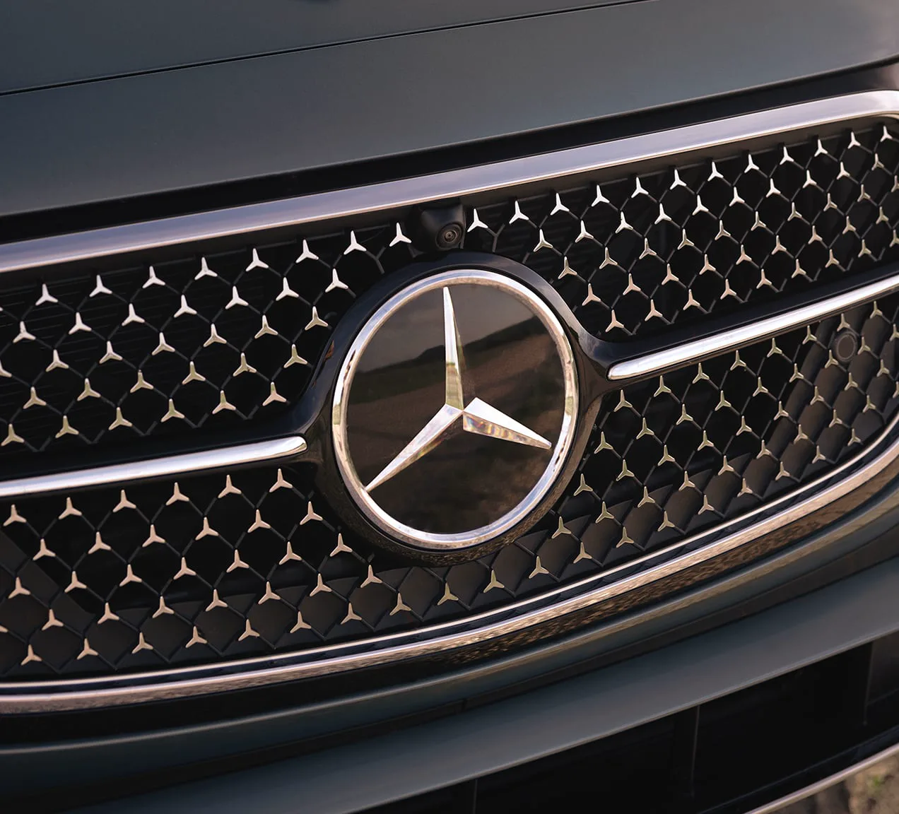 Star-pattern grille and central three-pointed star on a dark green Mercedes-Benz E-Class