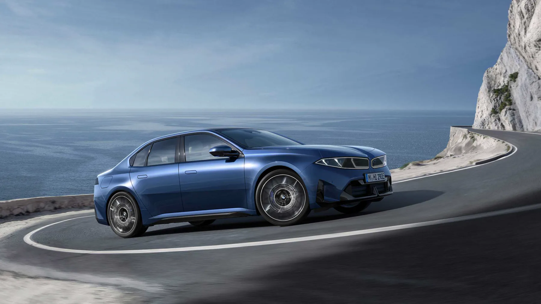 Blue 2026 BMW i3 50 xDrive, front three-quarter on a coastal road