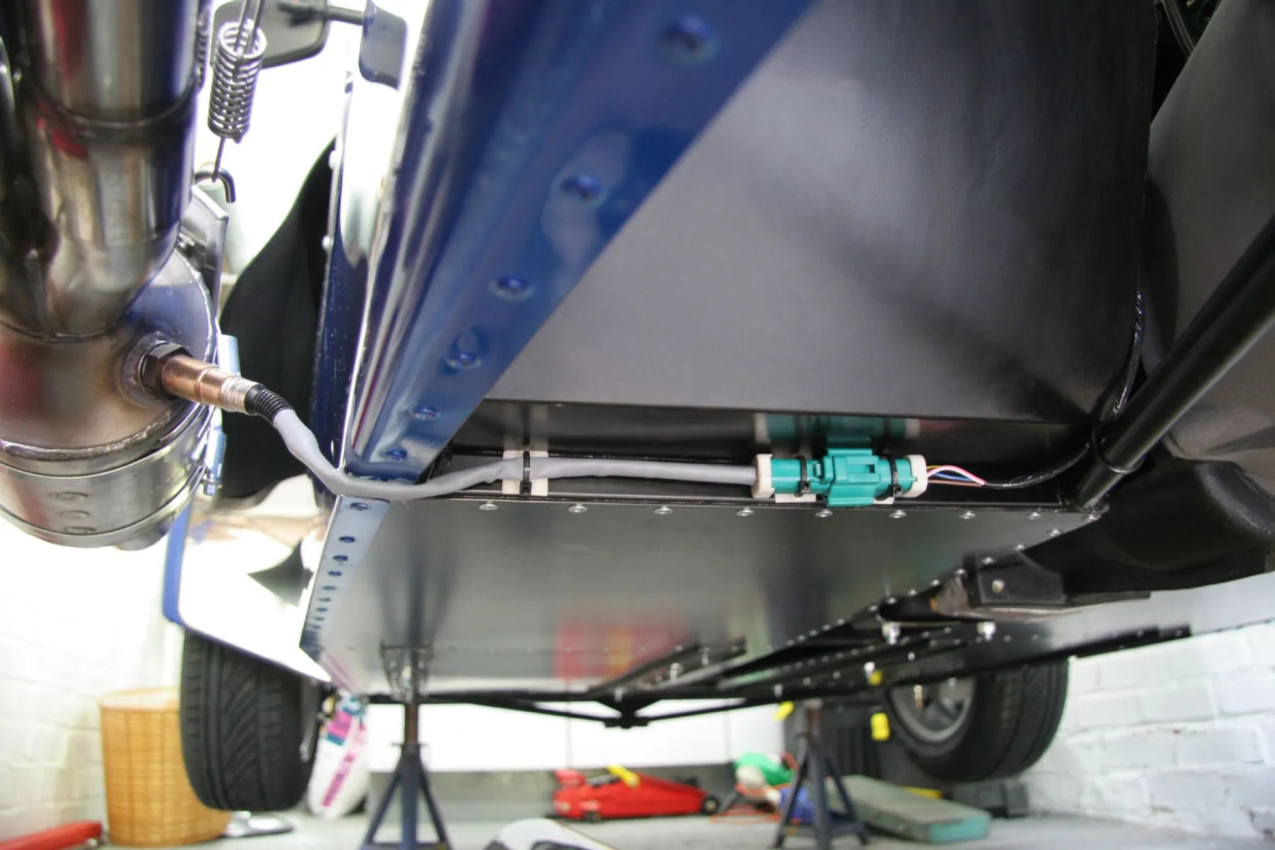Oxygen sensor threaded into a stainless exhaust pipe, harness clipped to the underbody