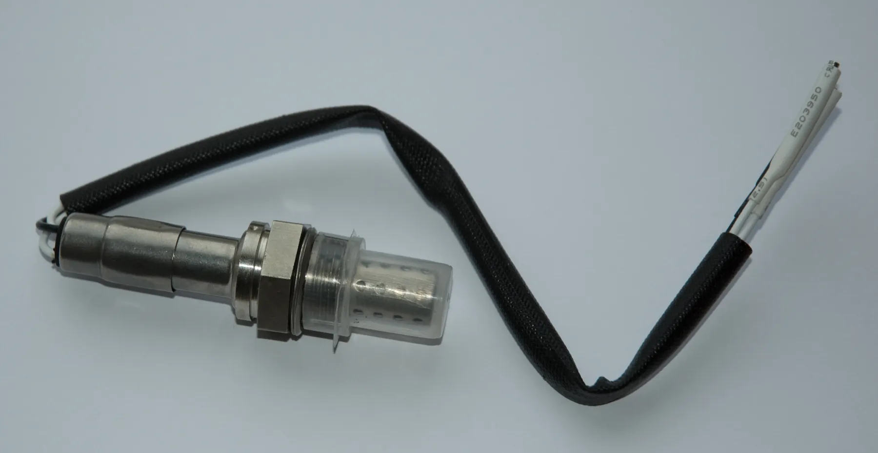 New oxygen sensor on a bench, hex, perforated tip, and three-wire harness