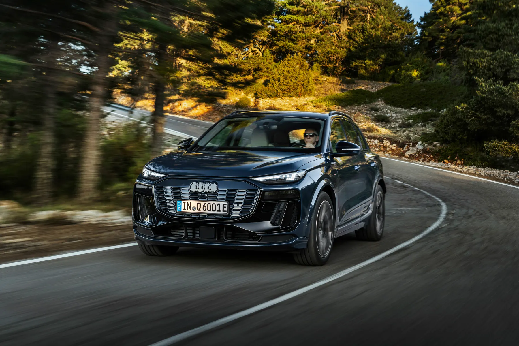 Blue 2026 Audi Q6 e-tron, front three-quarter on a forest road
