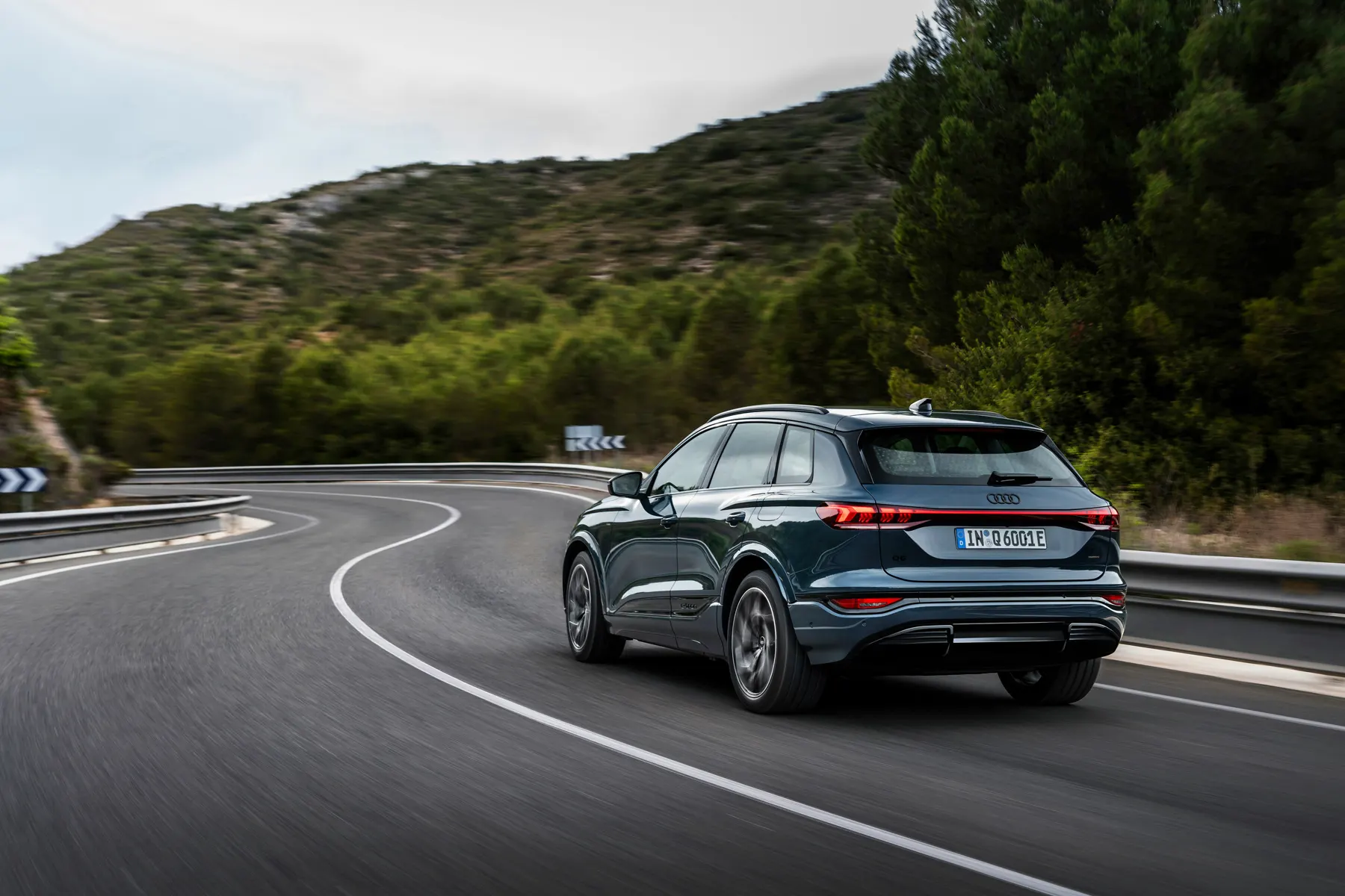 Blue 2026 Audi Q6 e-tron, rear three-quarter on a hillside road