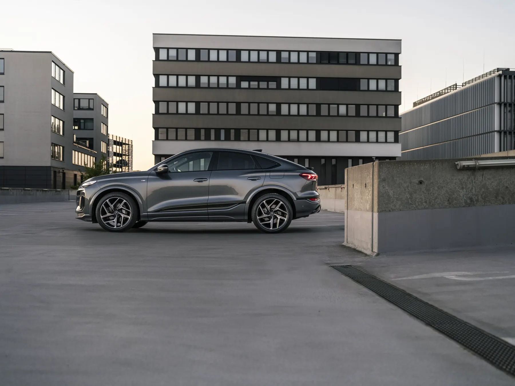 Gray 2026 Audi Q6 Sportback e-tron in side profile on a parking deck