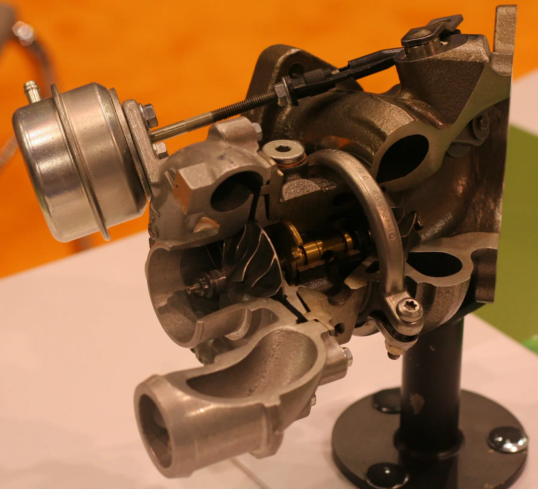 Cutaway turbocharger with a silver actuator can and rod across the housings