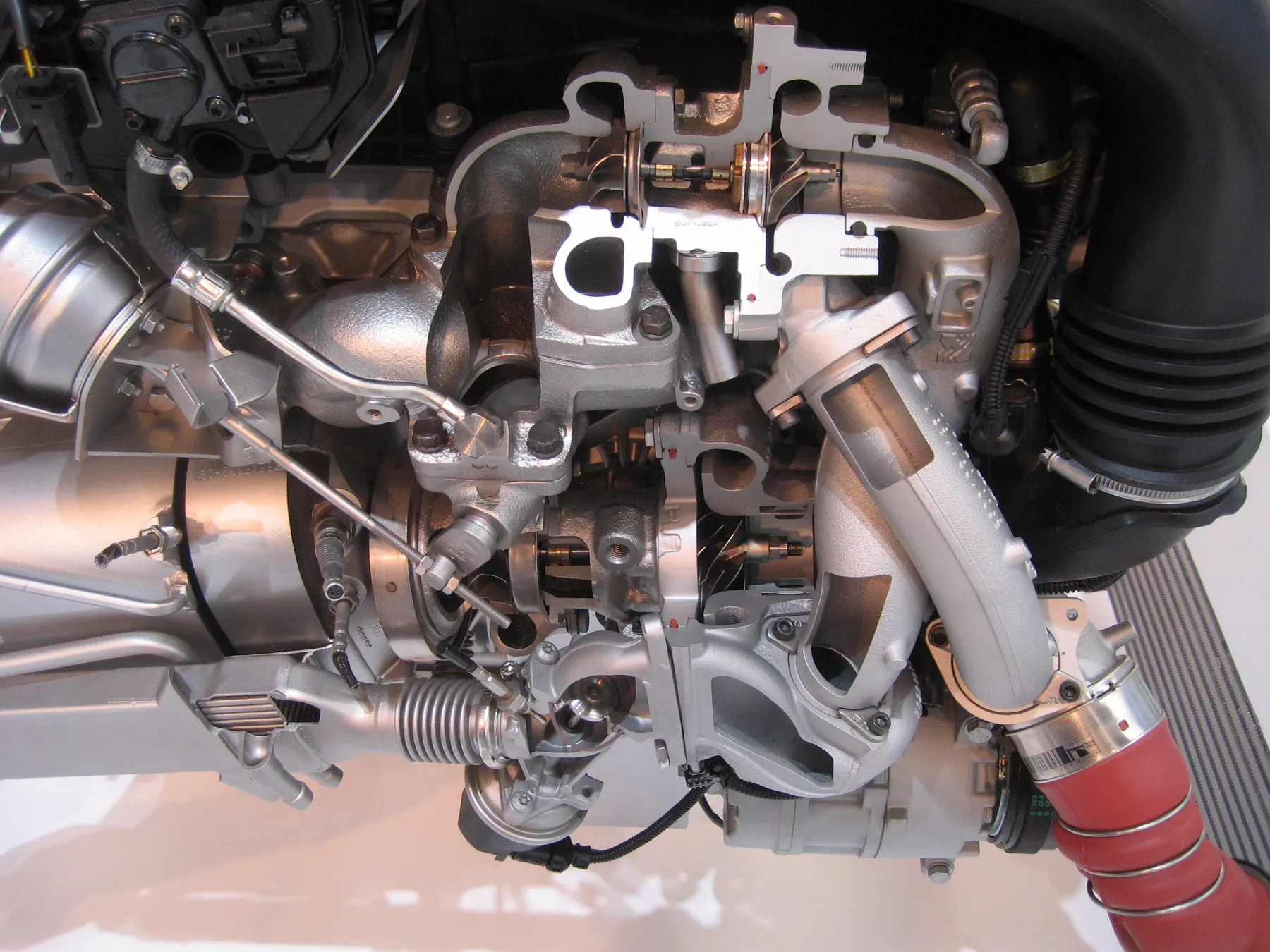 Cutaway turbo engine with a silver actuator can, hose, and rod beside the turbine housing