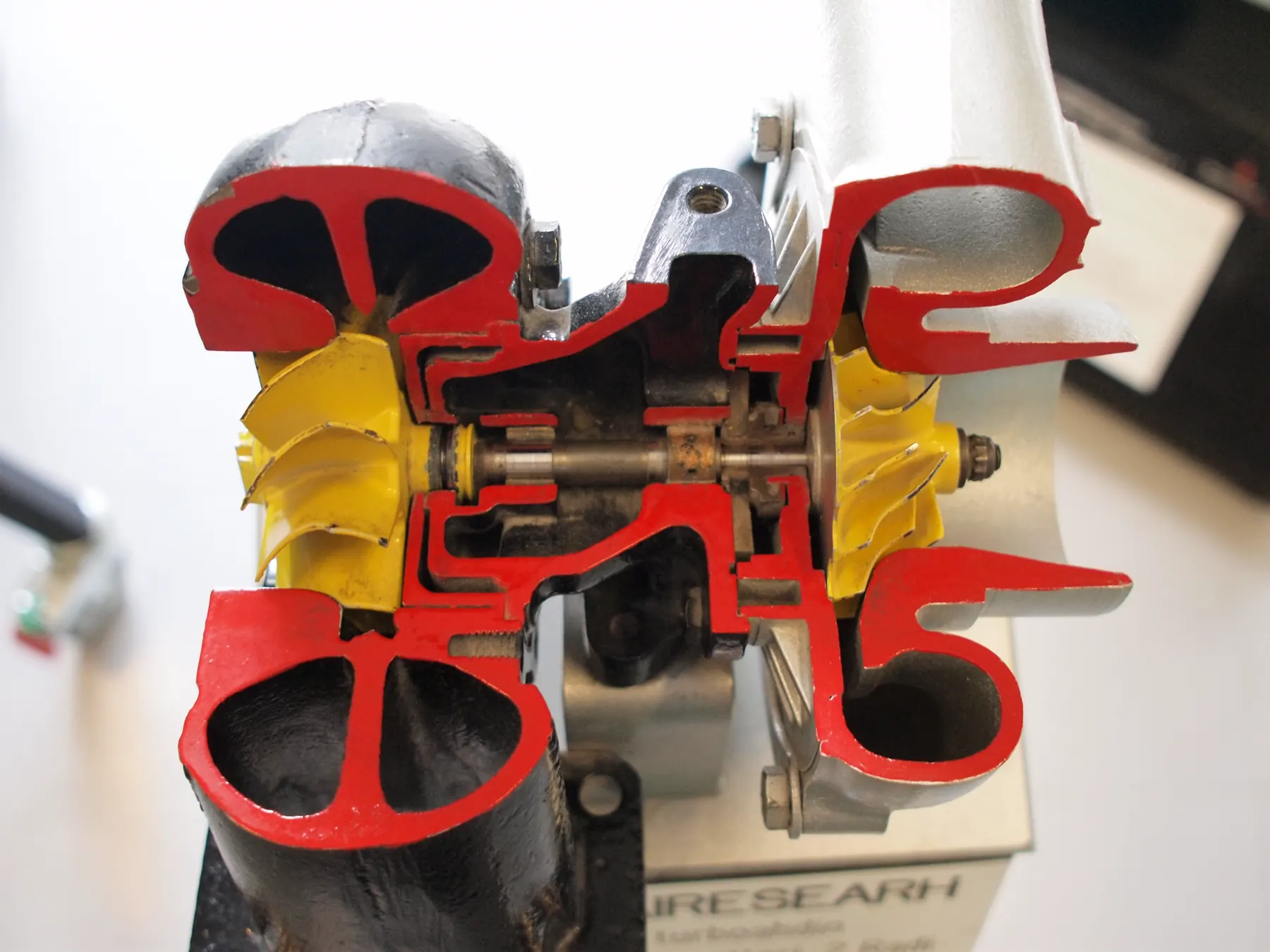 Sectioned turbocharger with red-cut housings and yellow turbine and compressor wheels